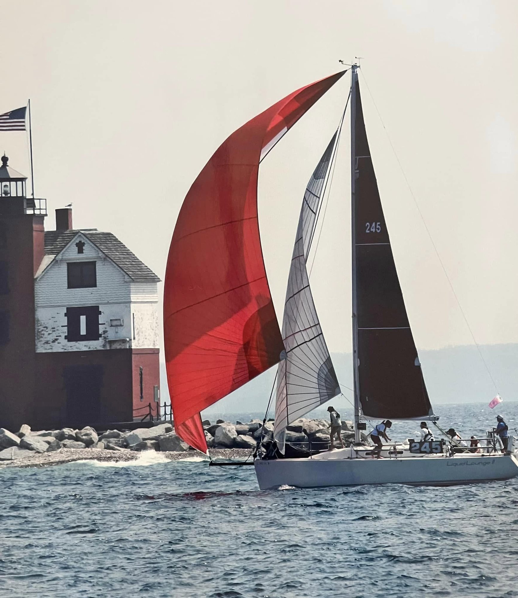 Liquid Lounge II, a J/109, passing Round Island Lighthouse with a red spinnaker and a twisted spinnaker staysail